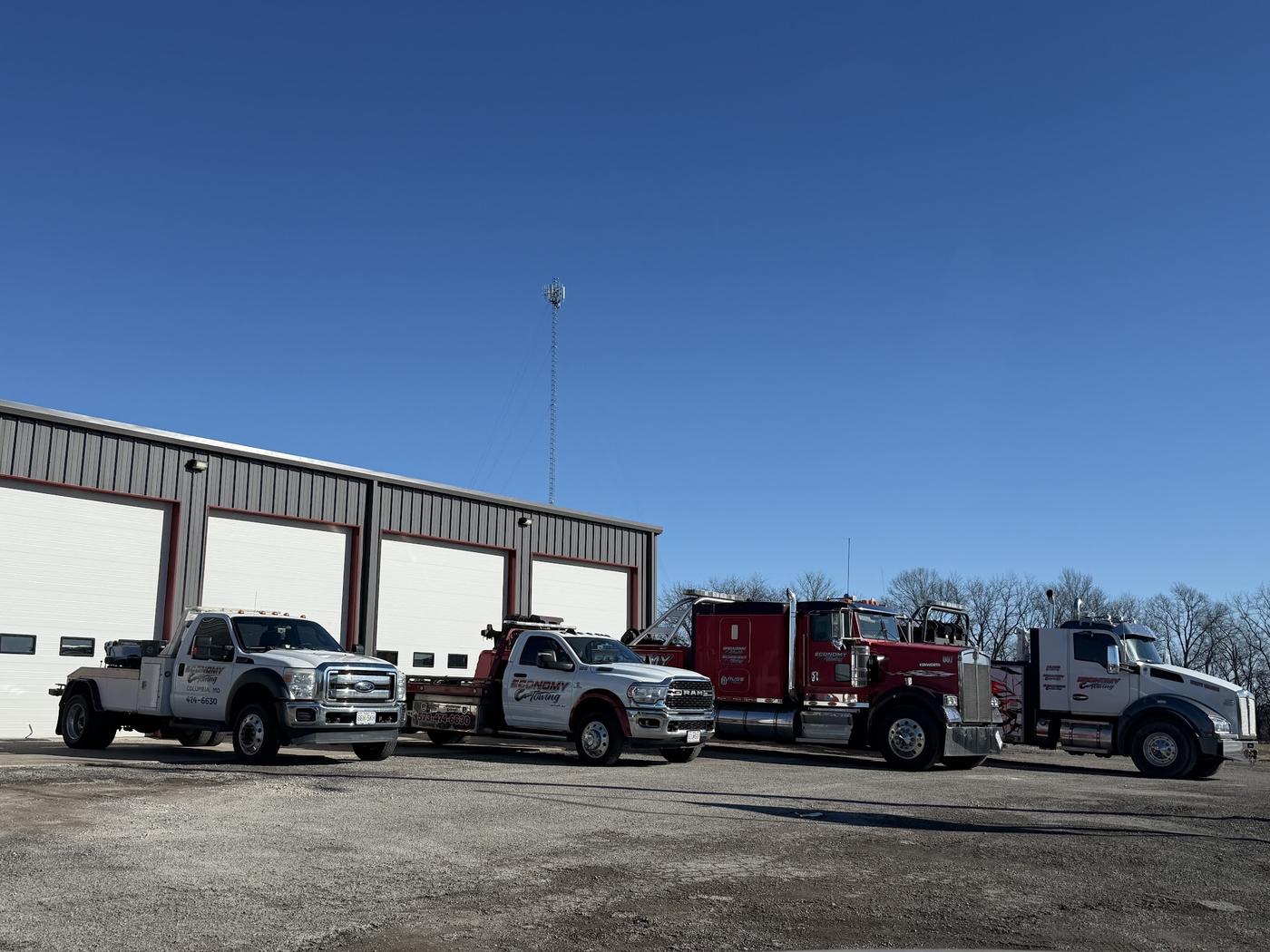 Four Economy Towing trucks lined up outside the shop bay doors