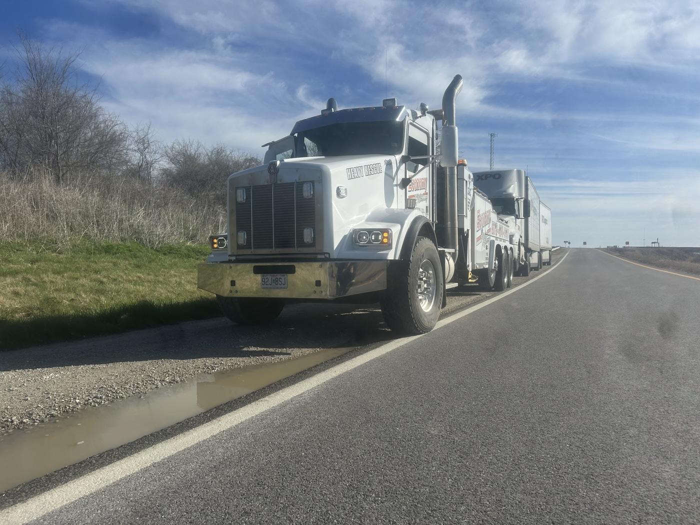 Economy Towing heavy wrecker towing a loaded semi trailer along a highway